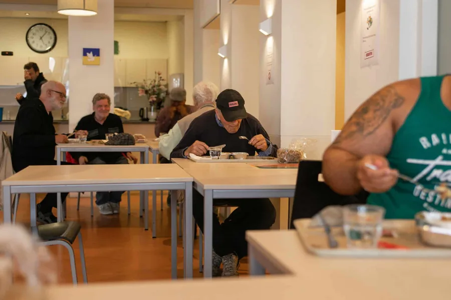 Gasten aan tafel tijdens de warme maaltijd in het aanloopcentrum